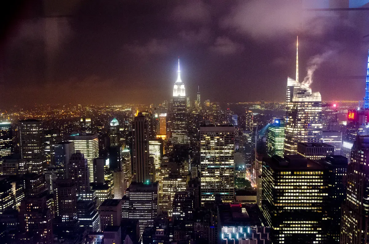 Midtown towers lit at night, seen from an open-top NYC night bus tour