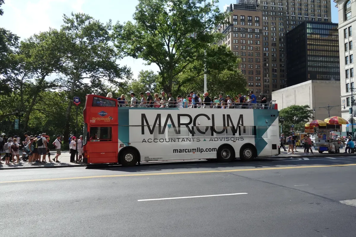 A red open-top double-decker at Battery Place on a NYC hop-on hop-off bus tour